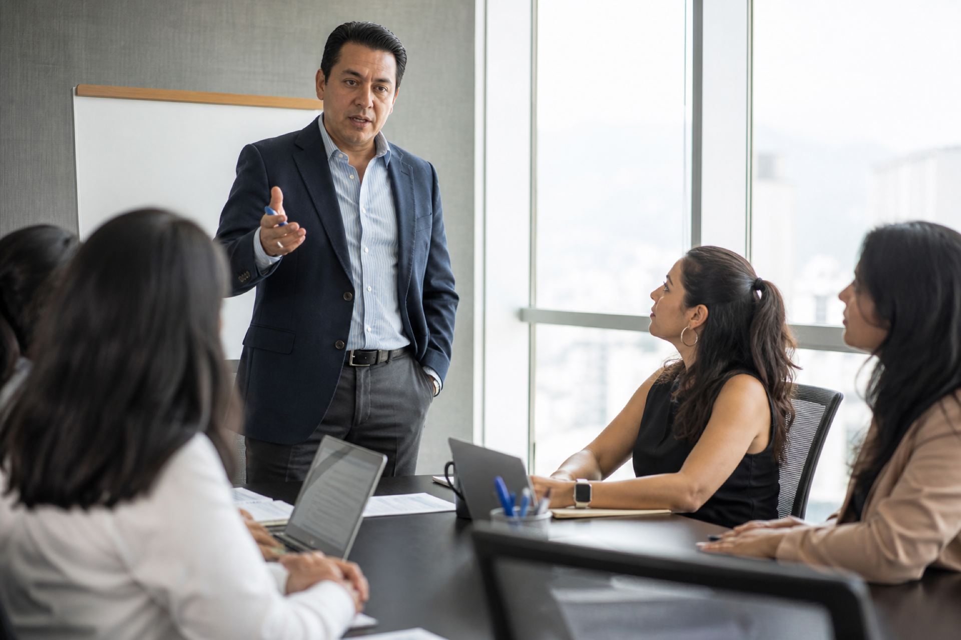 Consultor latino presentando estrategia a un equipo en oficina